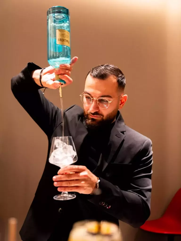 Barman versant un cocktail au bar de L'atelier